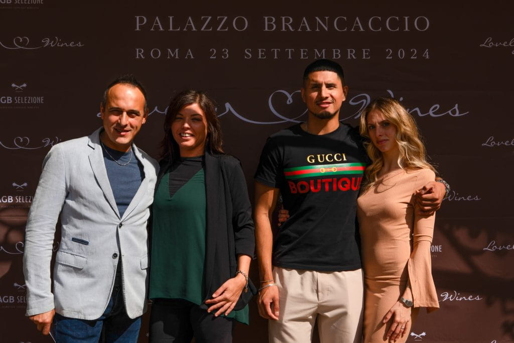 Quattro persone in piedi, sorridenti, davanti a un fondale marrone con testo bianco che recita Palazzo Brancaccio, Roma 23 settembre 2024. Due uomini e due donne sono in posa per la foto.