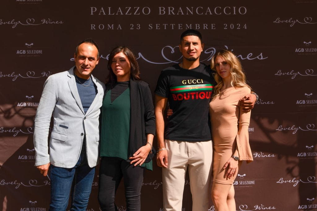 Quattro persone posano insieme davanti a un fondale marrone con testo bianco che promuove un evento a Palazzo Brancaccio a Roma il 23 settembre 2024. Due uomini e due donne sono in piedi, uno di fronte all'altro, rivolti verso l'obiettivo.